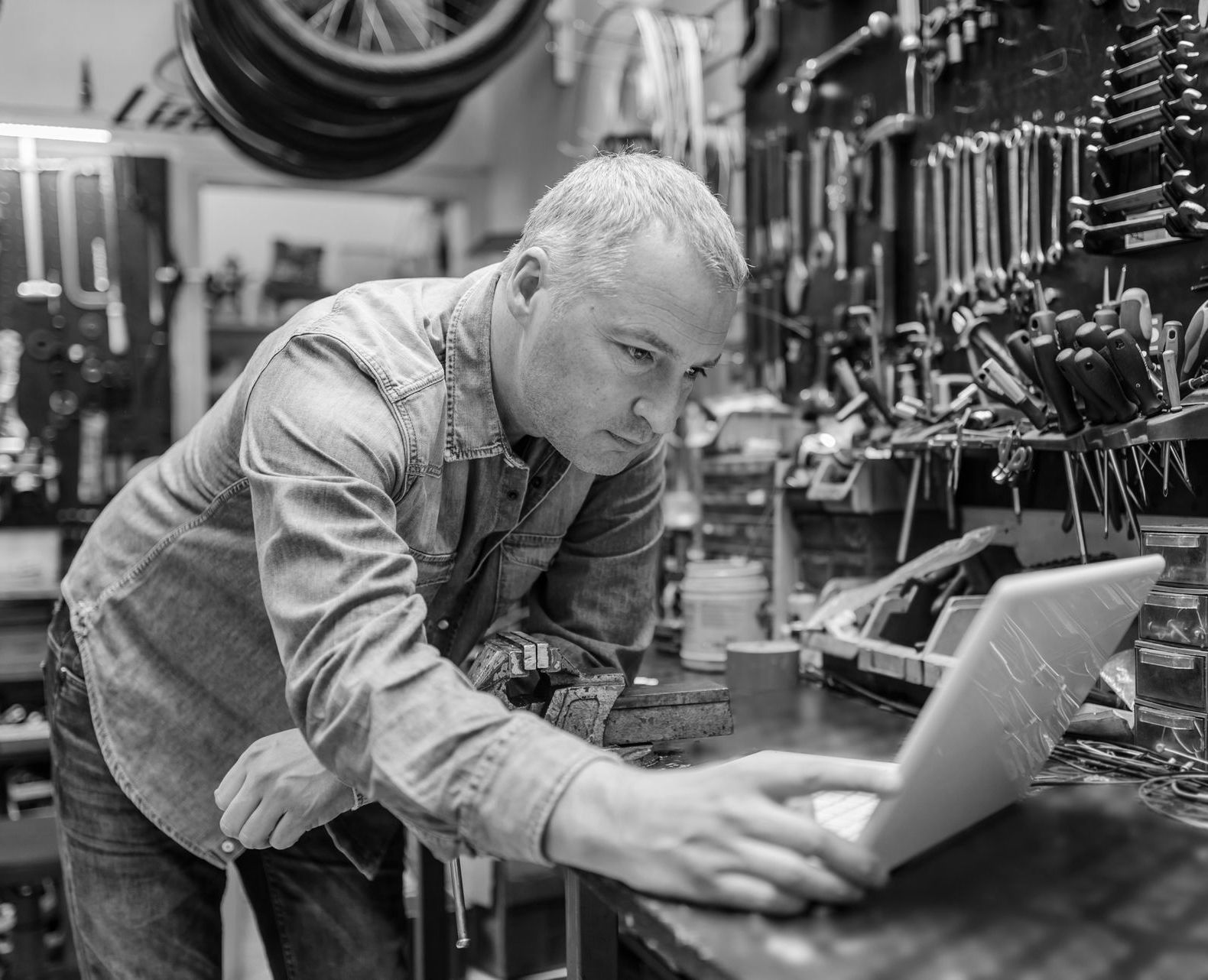 the bike shop owner working on a laptop, researching small business tech support options