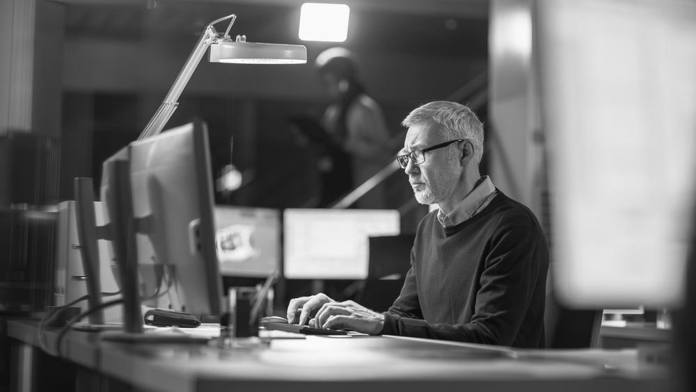 A man is sitting at a desk in front of a computer.