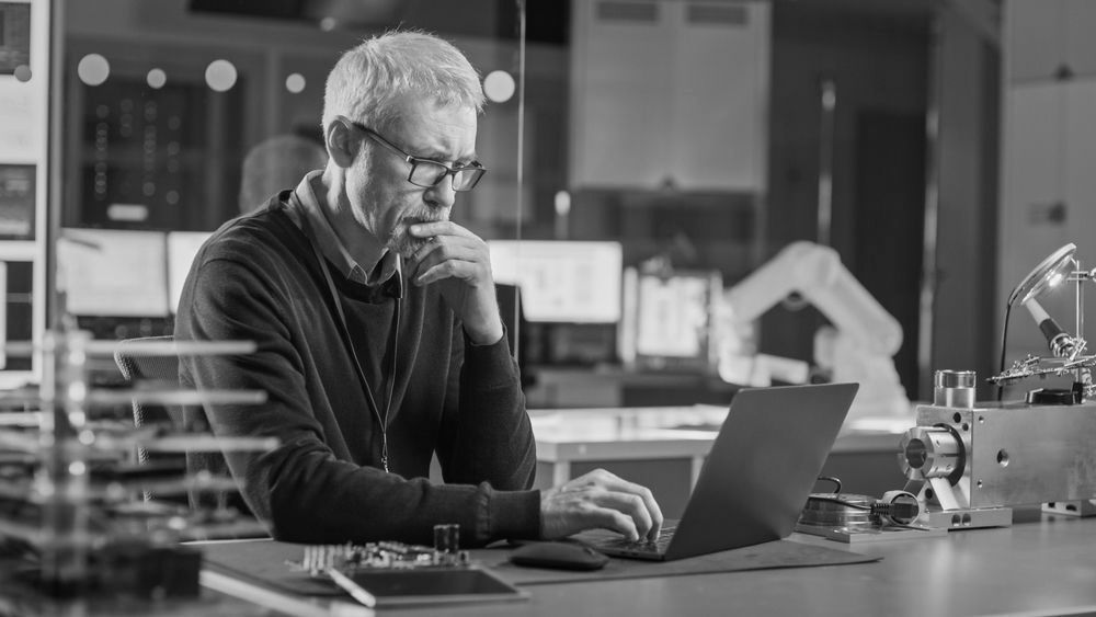 A man is sitting at a desk using a laptop computer.