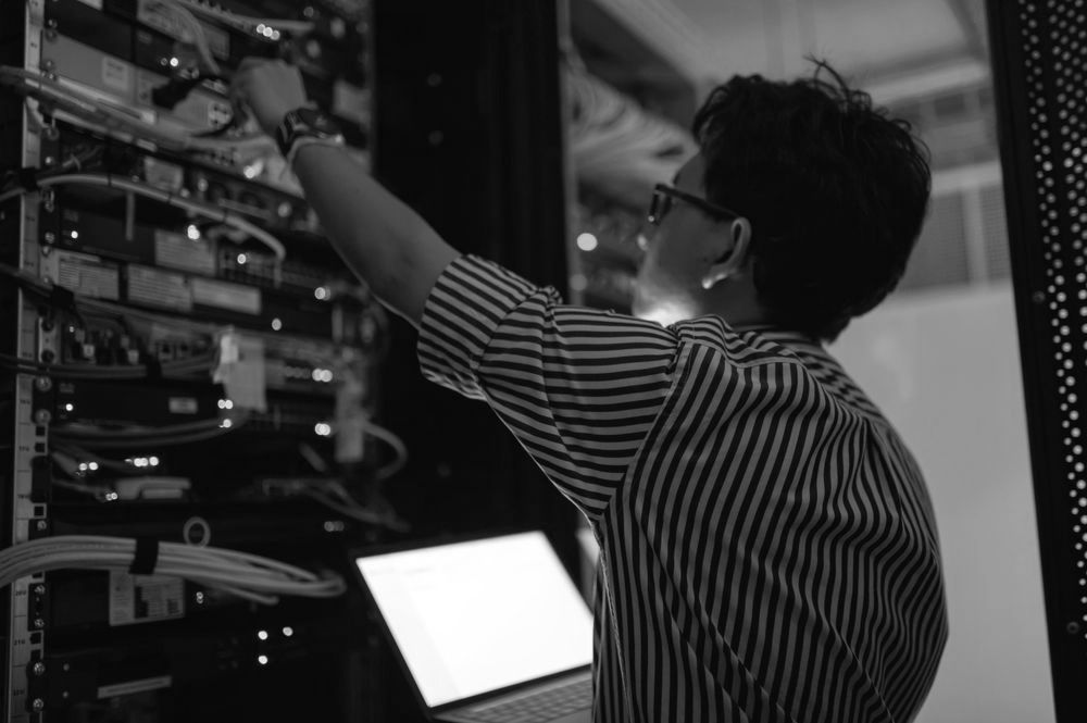 A black and white photo of a man working on a server.