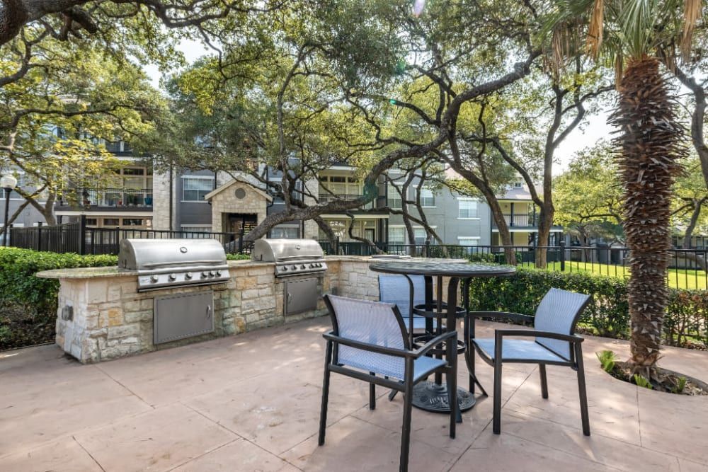 a patio with a table and chairs and a grill at Marquis at Deerfield in San Antonio, TX.