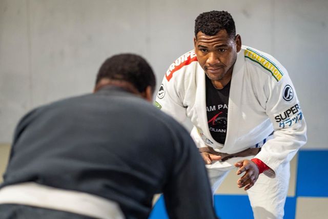 Man in white gi facing another person, ready to engage in a martial arts activity.