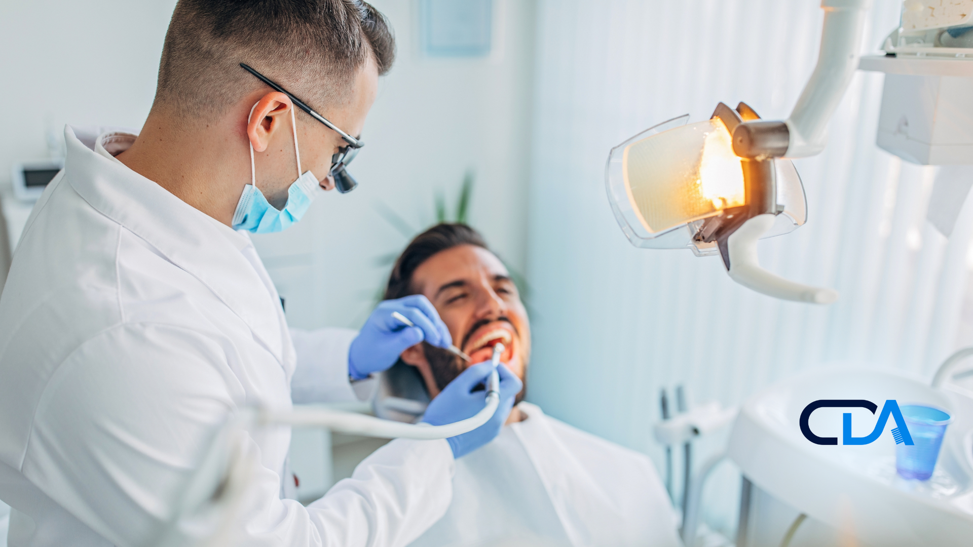 A dentist is examining a man 's teeth in a dental office.