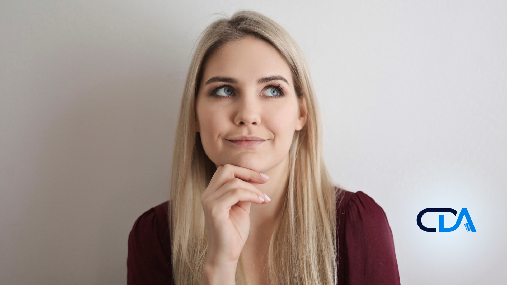 A woman is thinking with her hand on her chin.