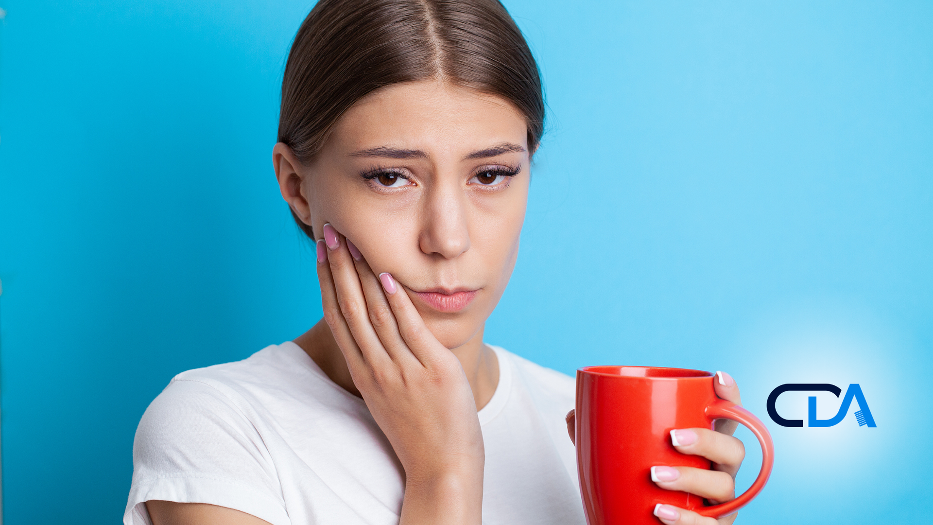 A woman is holding a red cup of coffee and has a toothache.