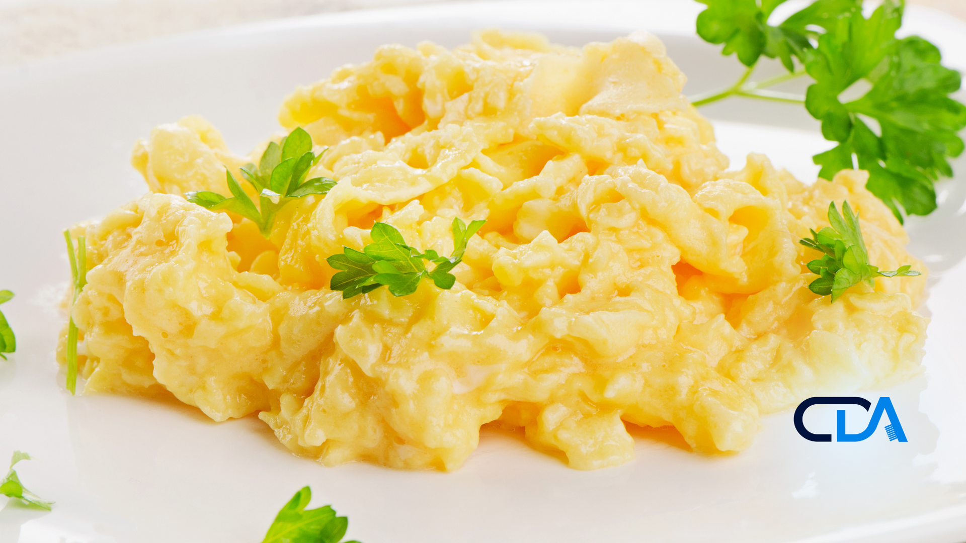 A white plate topped with scrambled eggs and parsley.