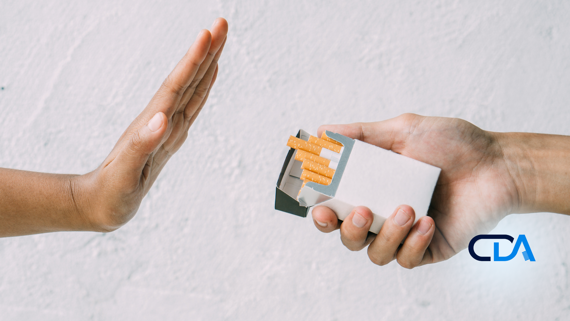 A person is refusing a pack of cigarettes from another person.