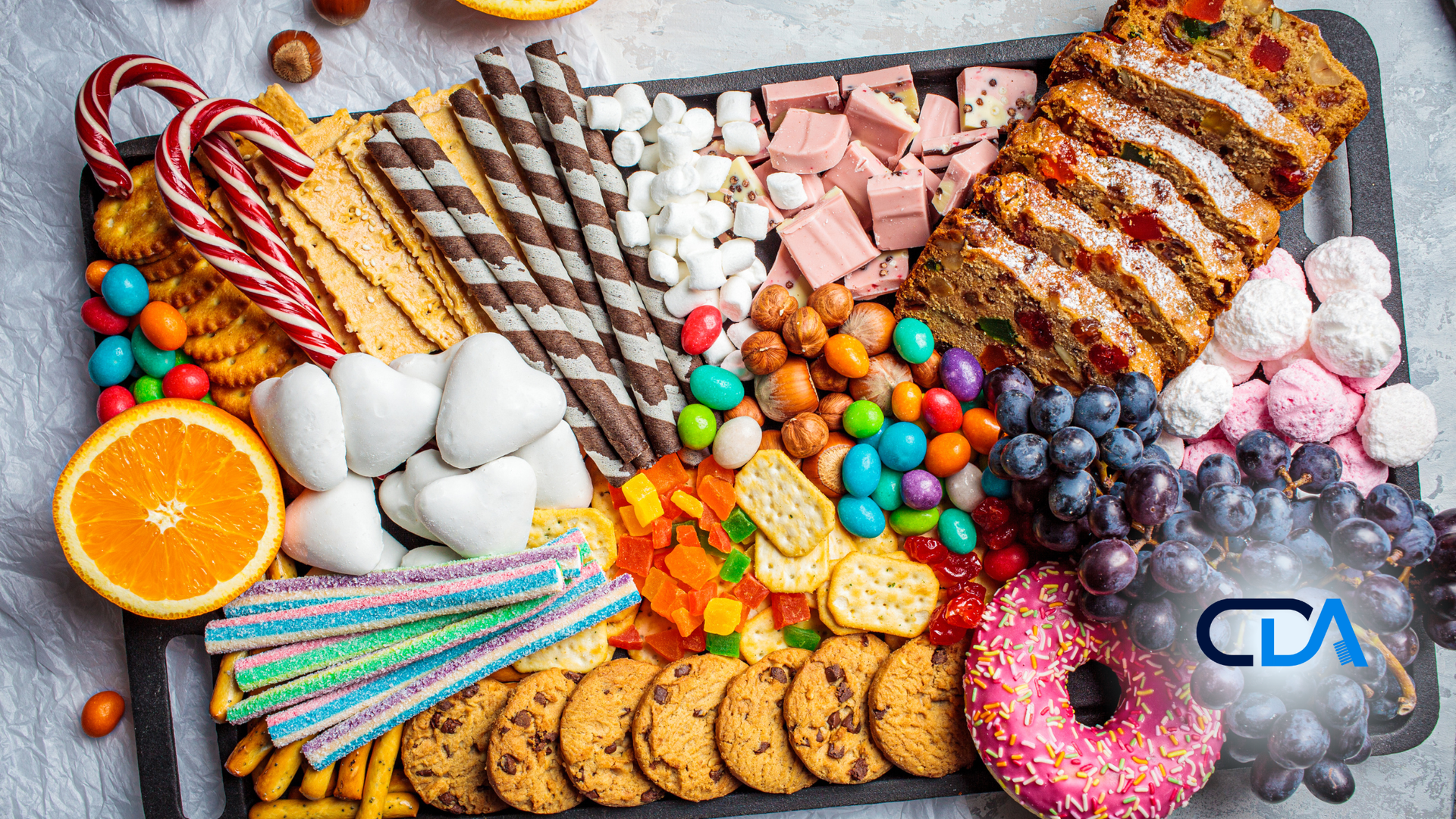 Dessert platter with cookies, candy, fruit, and baked goods in a colorful arrangement.