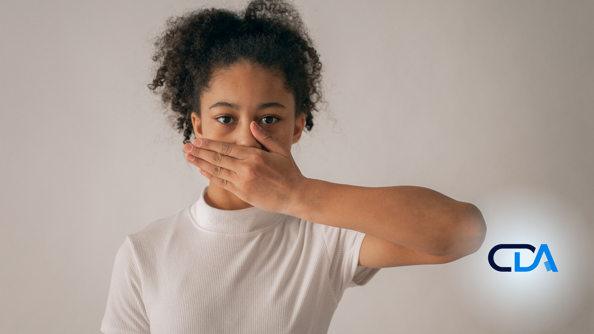 A woman is covering her mouth with her hand.