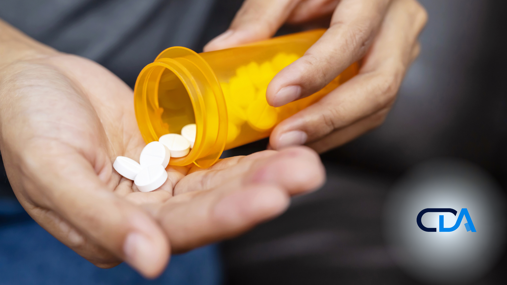 A person is pouring pills from a bottle into their hand