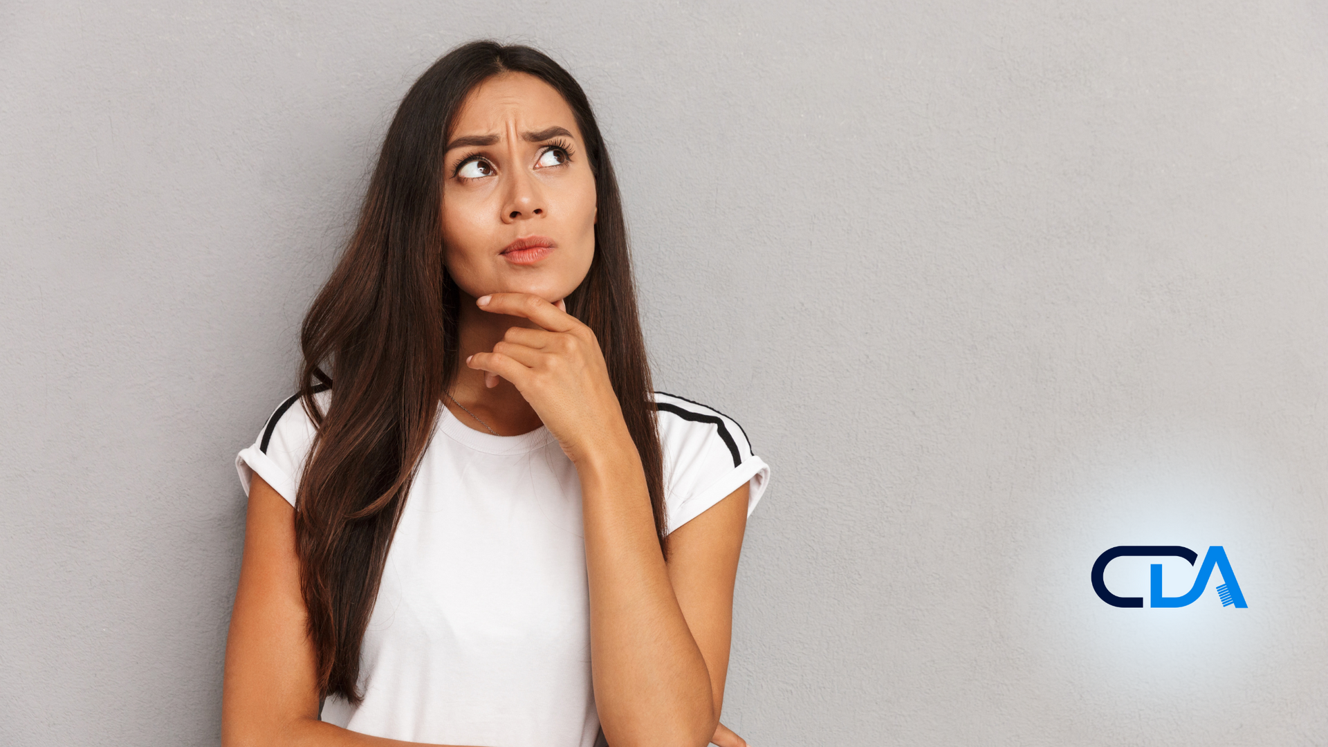 A woman is holding her hand to her chin and looking up.