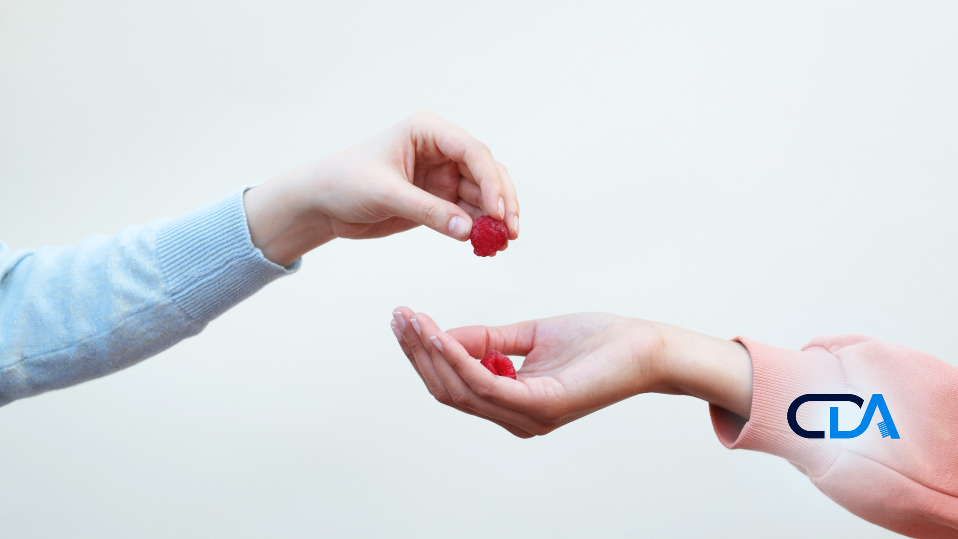 Two hands: one holding out a red item, the other receiving it.