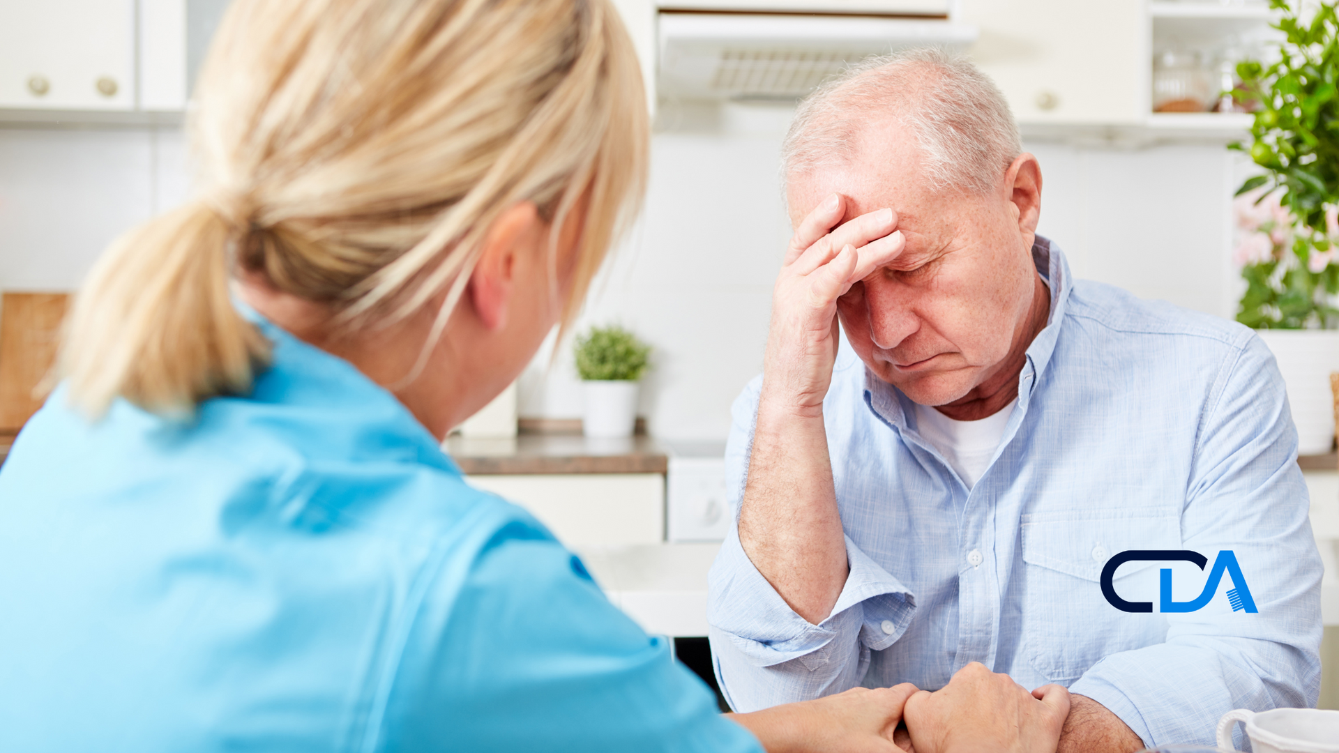 An elderly man is sitting at a table talking to a nurse.