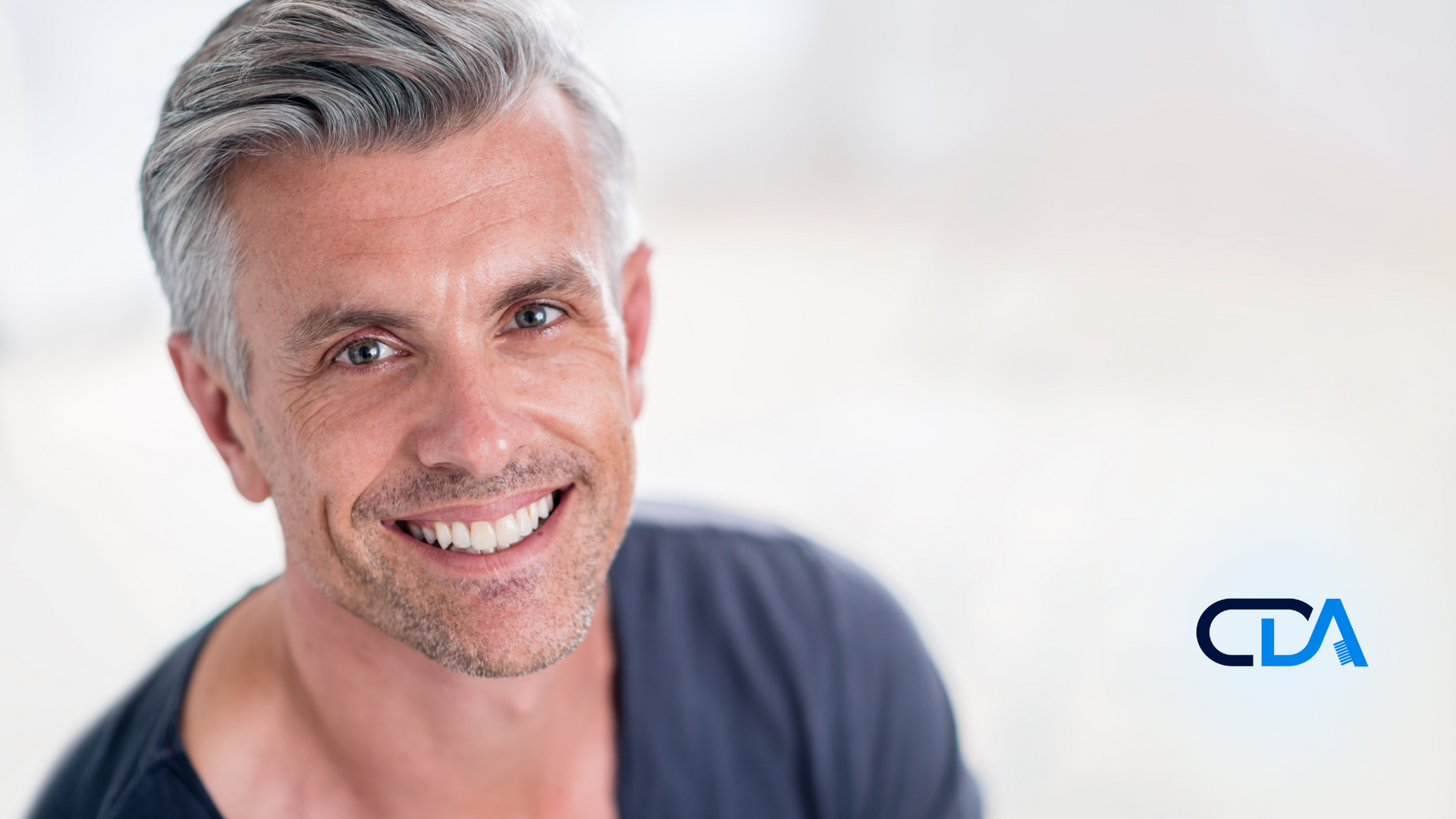 A man with gray hair and a beard is smiling for the camera.