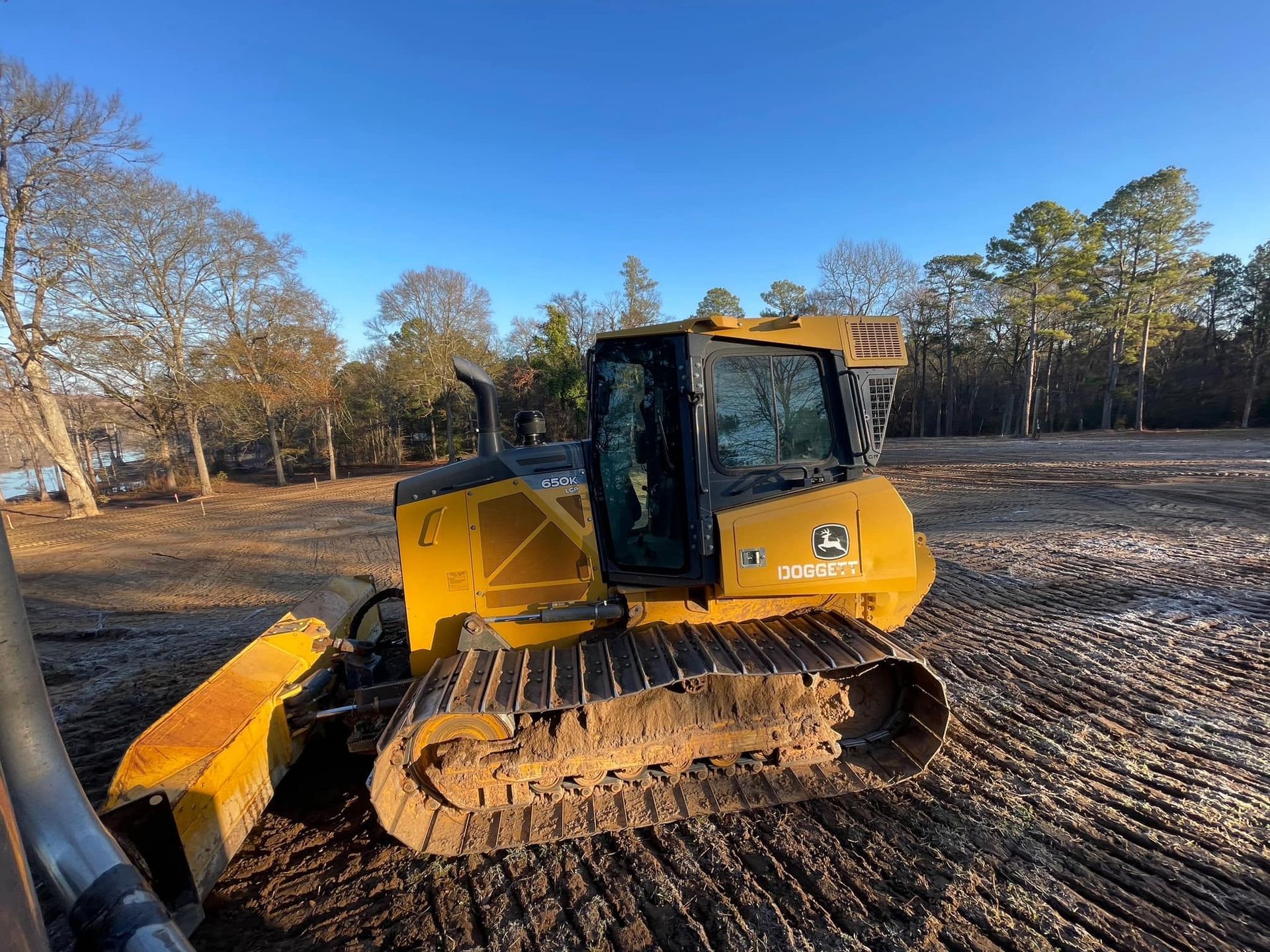 A yellow bulldozer is sitting in the middle of a dirt field.