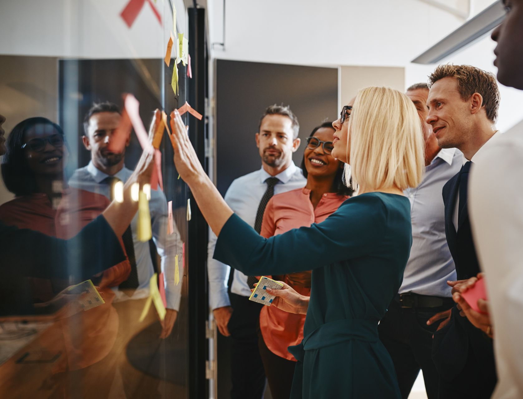 A diverse group of professionals in business attire collaborate around a conference table during a meeting.