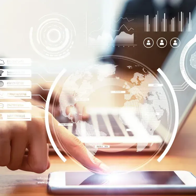 Person using a laptop and phone, interacting with holographic data visualizations of a world map.