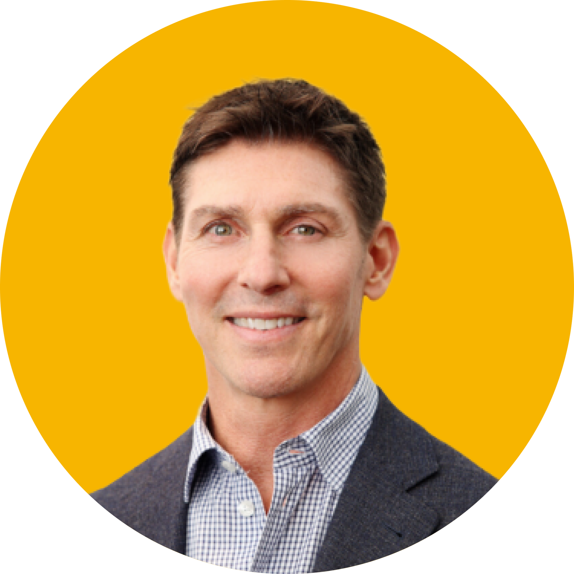 A man with short brown hair, wearing a patterned button-down shirt and a dark blazer, smiles against a yellow background.