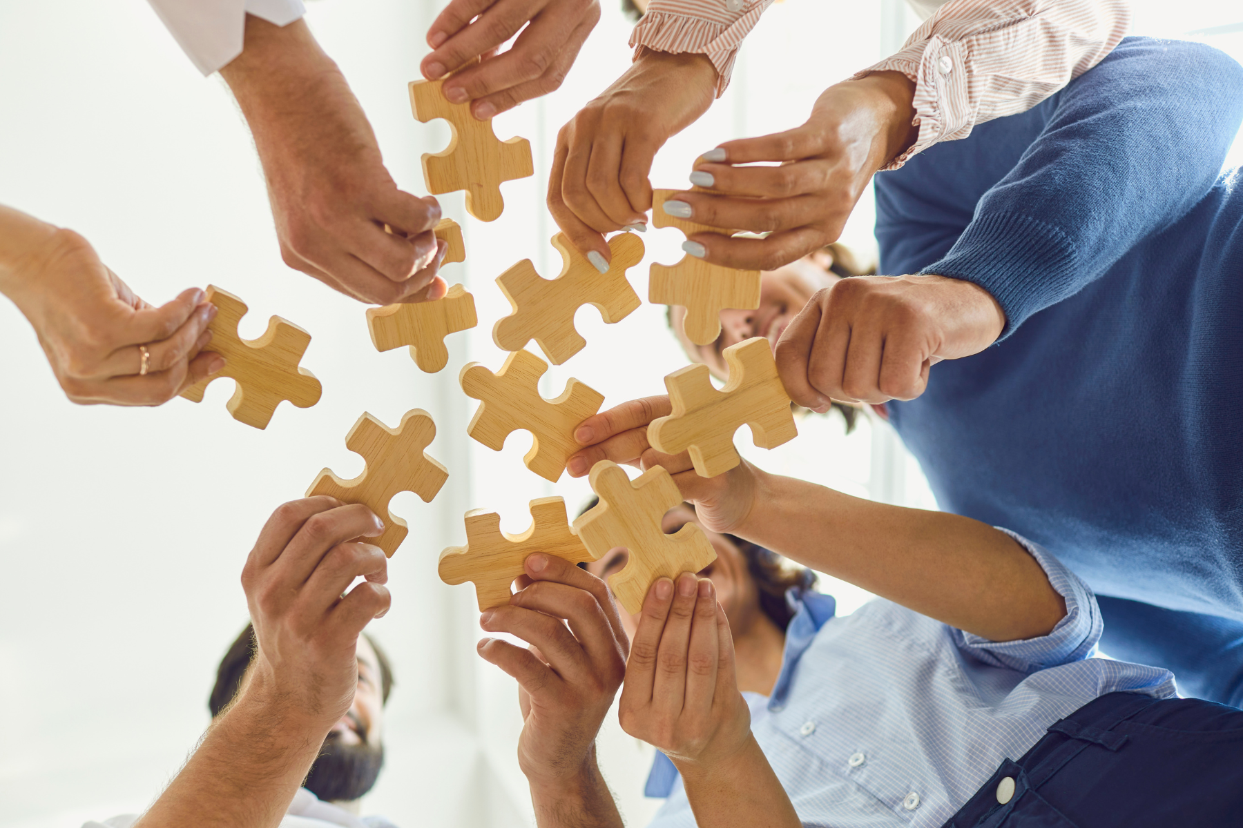 IT professional hands reaching for wooden puzzle pieces, teamwork concept.