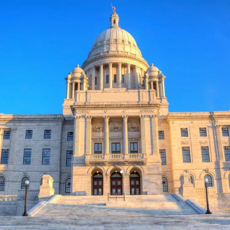 Rhode Island State House, white marble building with dome under clear blue sky.