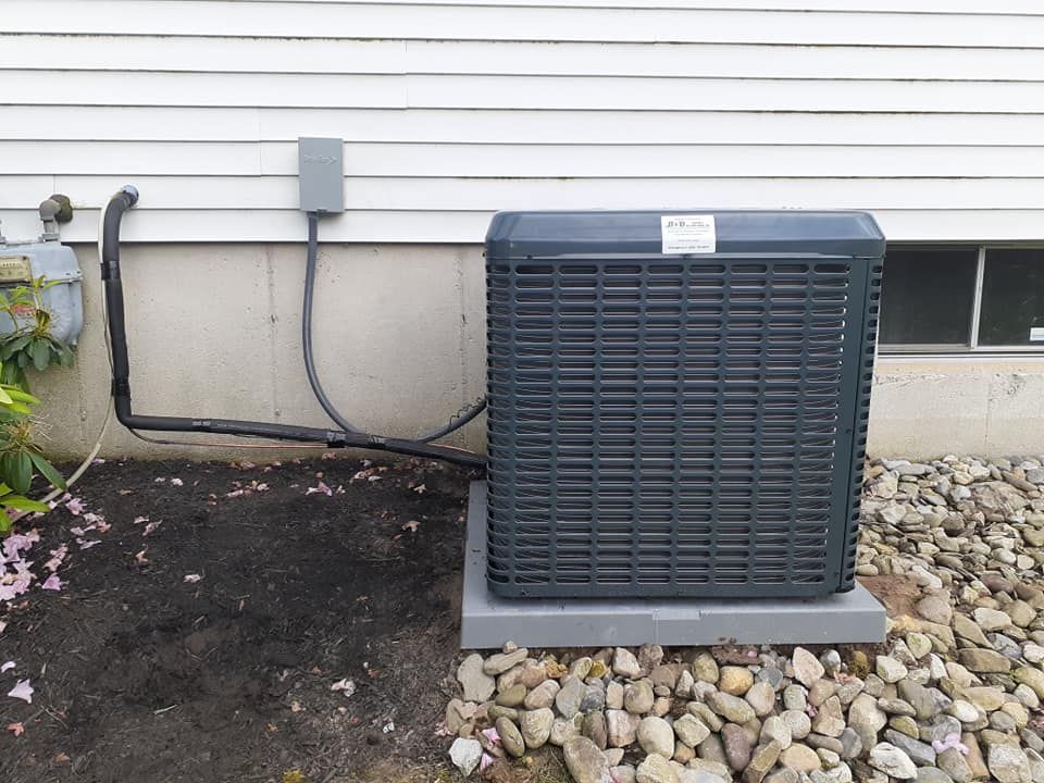AC unit on a concrete pad outside a building, with electrical box and gas line visible.