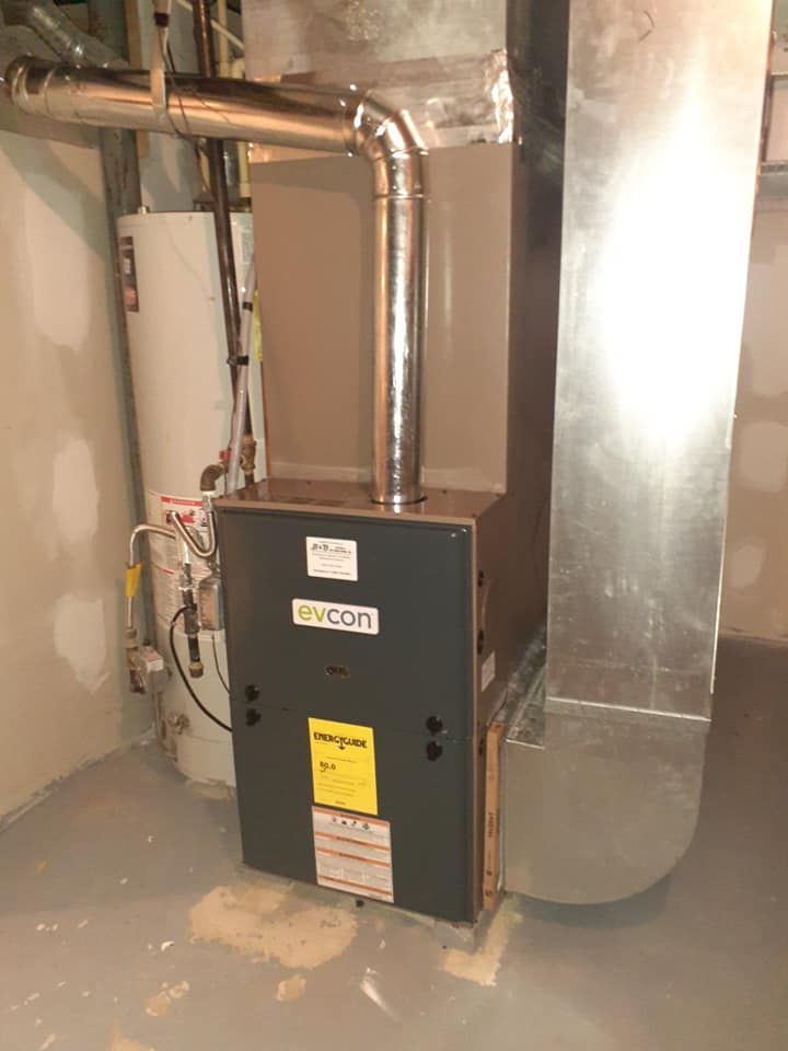 A gas furnace and water heater in a basement. The furnace is gray, with a yellow energy guide label.