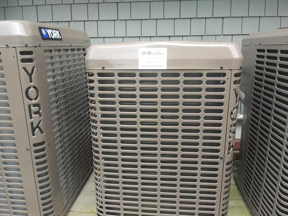 Three brown York air conditioning units against a shingle wall.