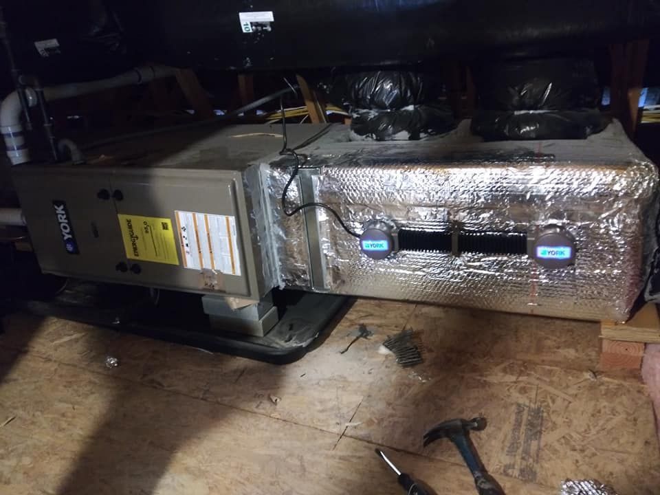 HVAC unit in an attic. Ductwork is wrapped in foil insulation. Two digital sensors are attached.