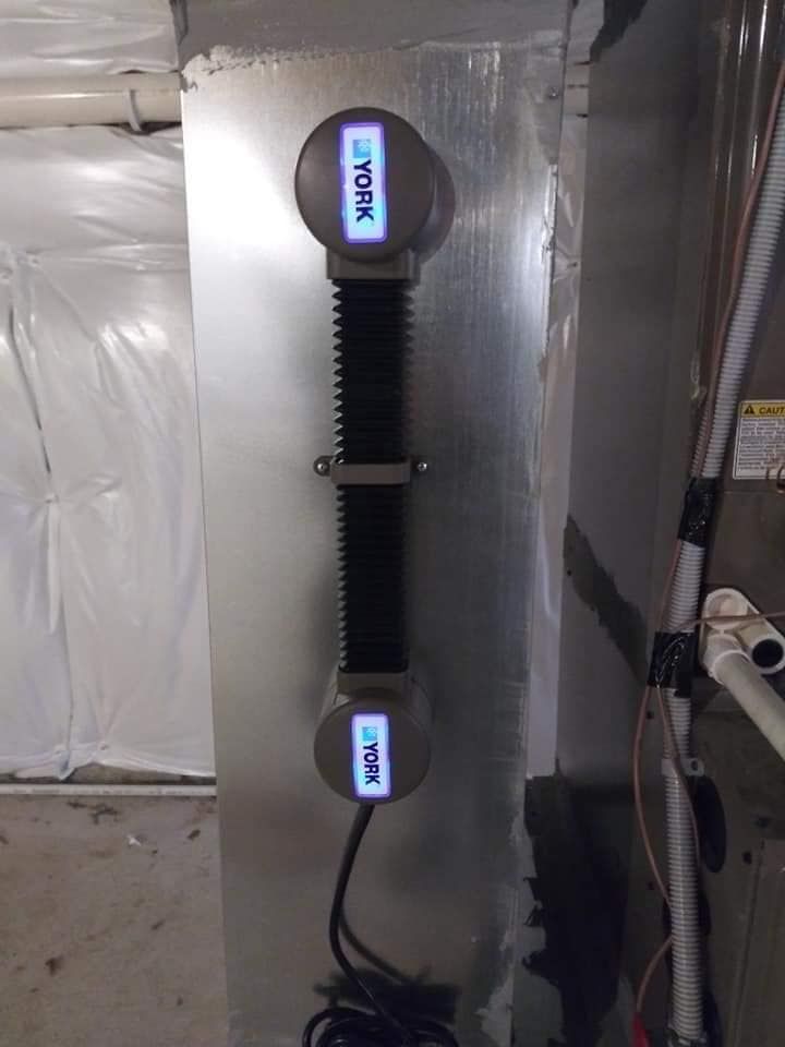 York HVAC air purification system installed on ductwork. Black, flexible tube with two gray units.