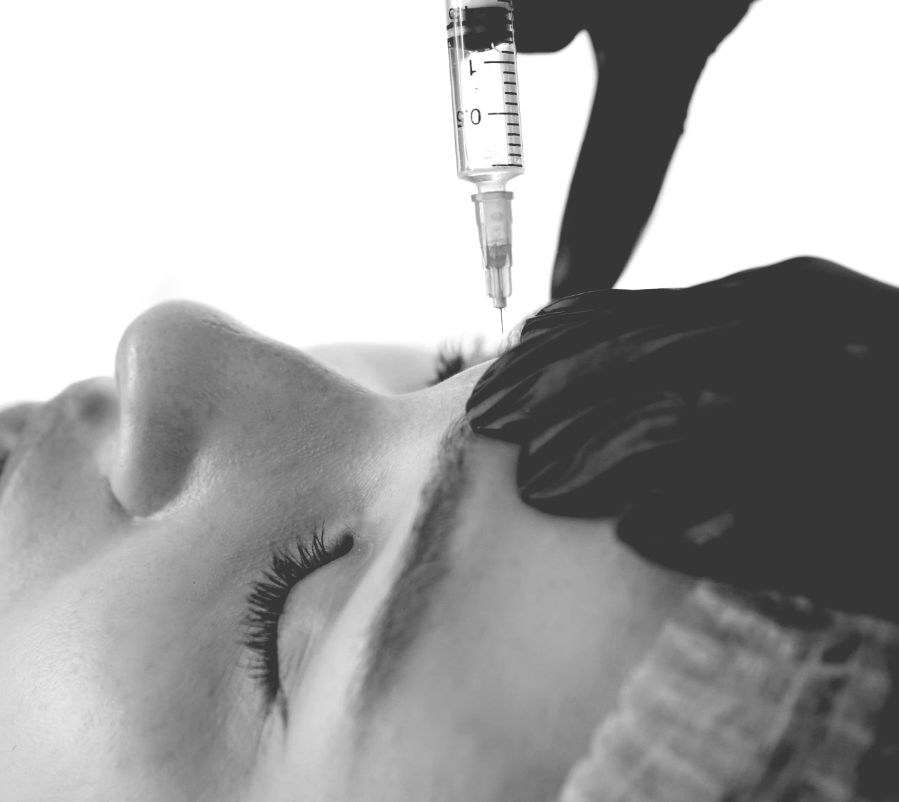 Person receiving an injection near their eyebrow; hands hold syringe.