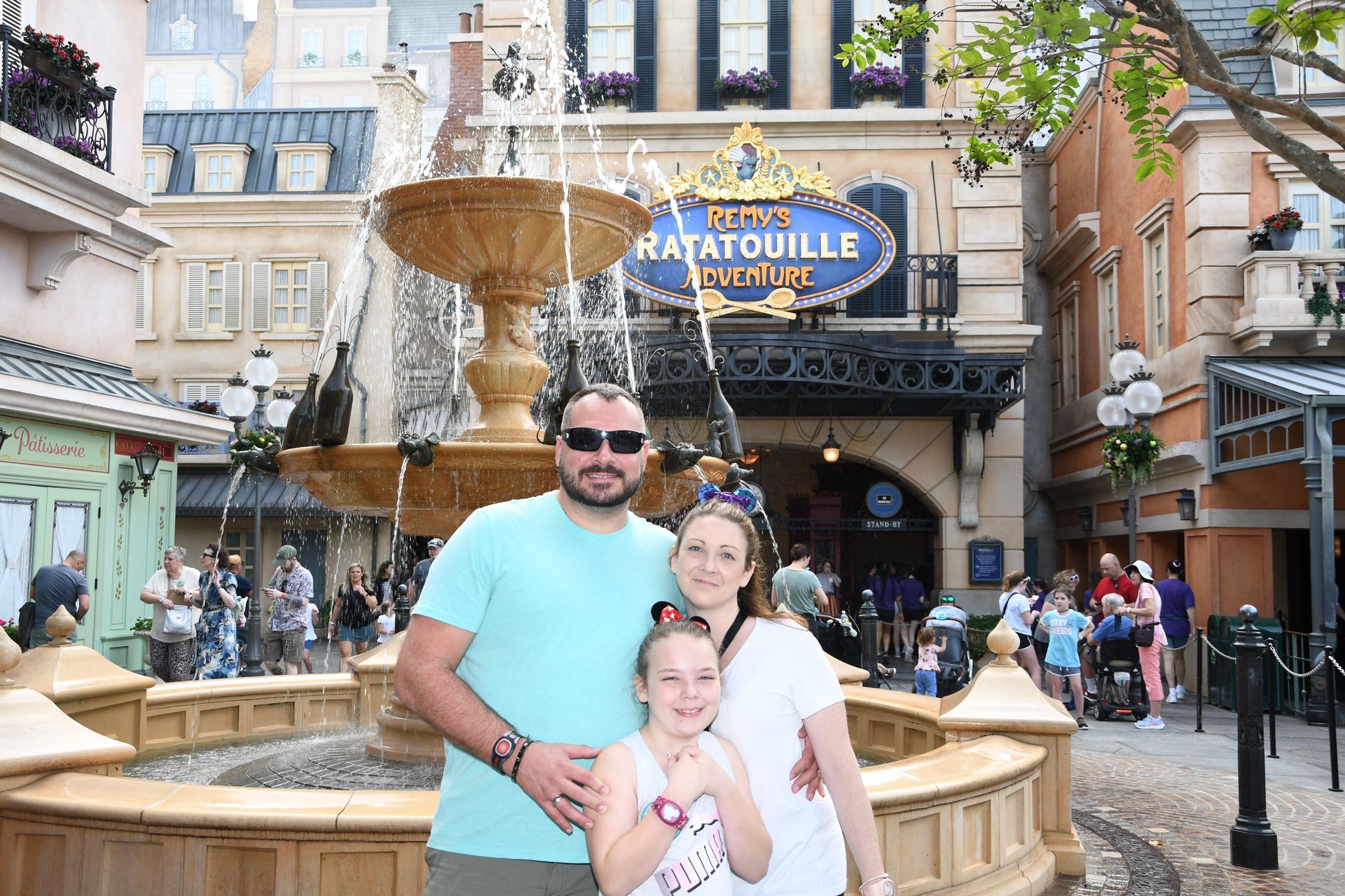 Family of three smiling in front of a fountain and