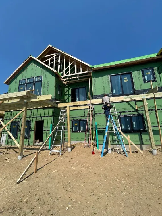 Green house under construction with ladders and scaffolding against a blue sky