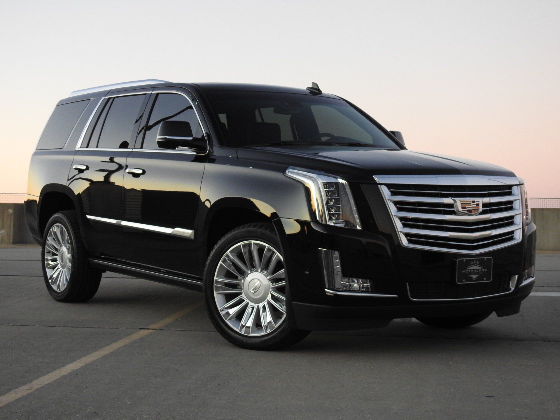 A black cadillac escalade is parked in a parking lot.