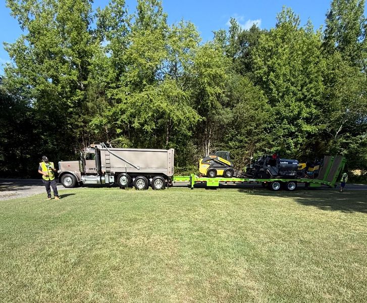 A dump truck with a trailer attached to it is parked in a grassy field.