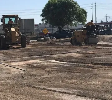 Two construction vehicles are working on a dirt road.