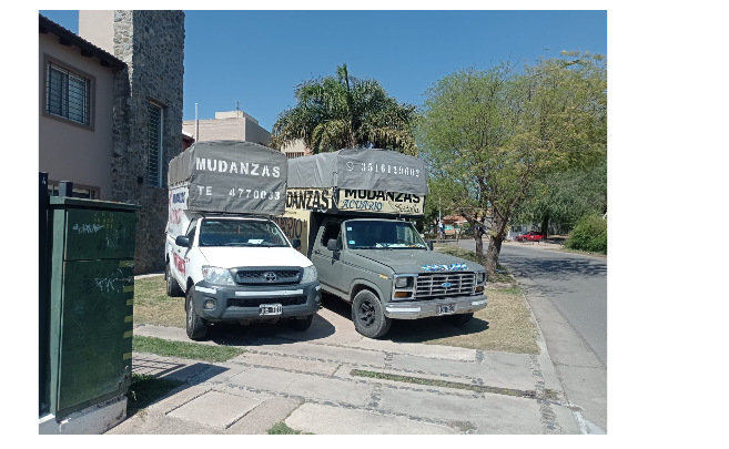 Dos camionetas estacionadas en una calle residencial. Ambas tienen la parte trasera cubierta con texto. Un día soleado.