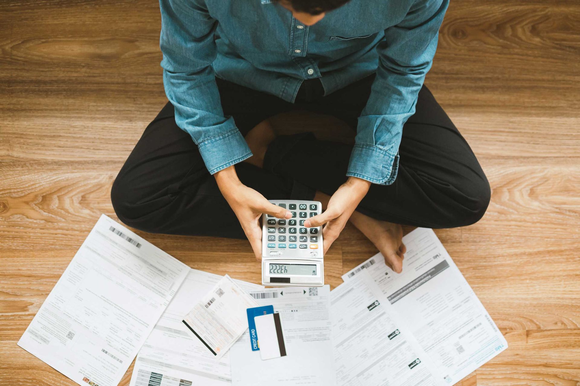 Top view man sitting on the floor stressed and confused by calculate expense from invoice or bill.