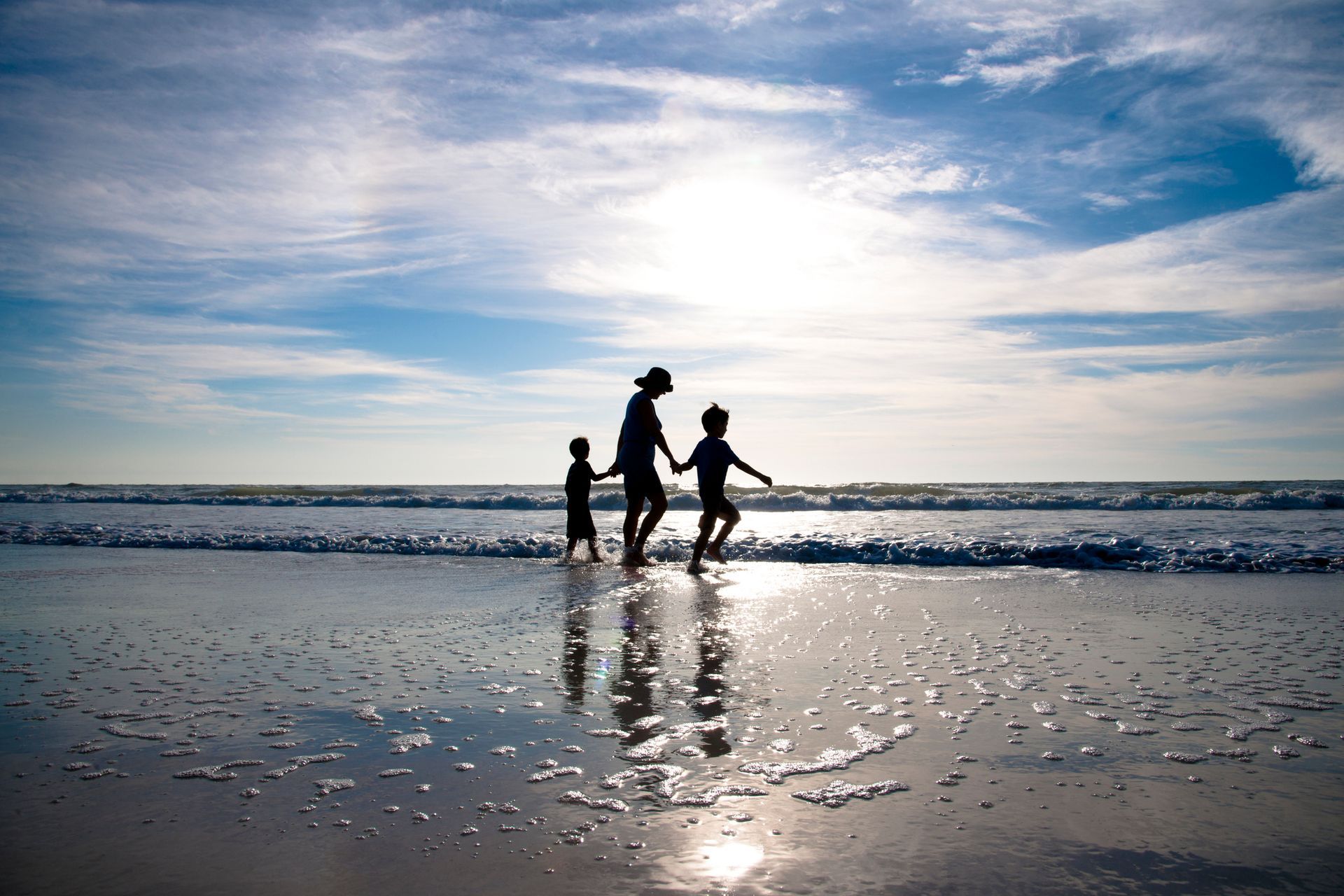 A woman walking at the beach with her two children.