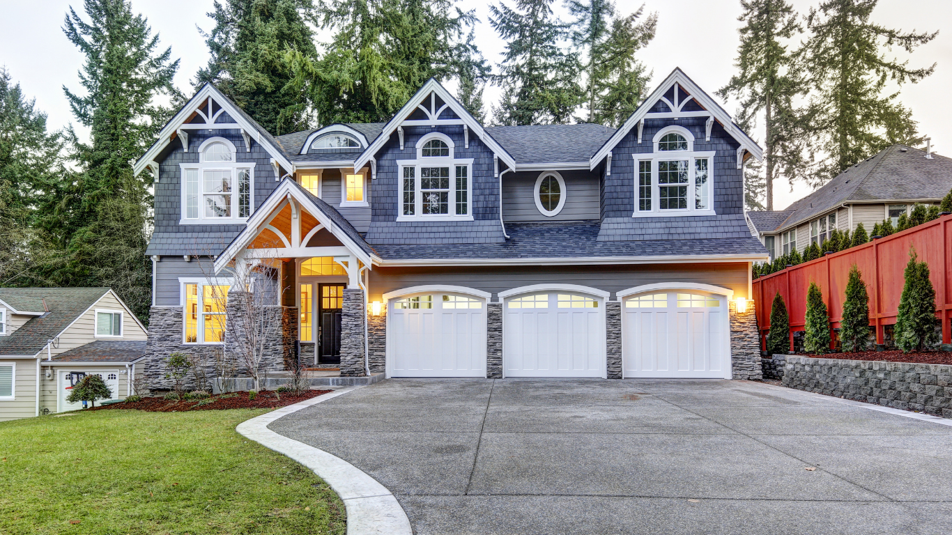 Living room with wood paneling, fireplace, dark couches, large windows, and chandelier.