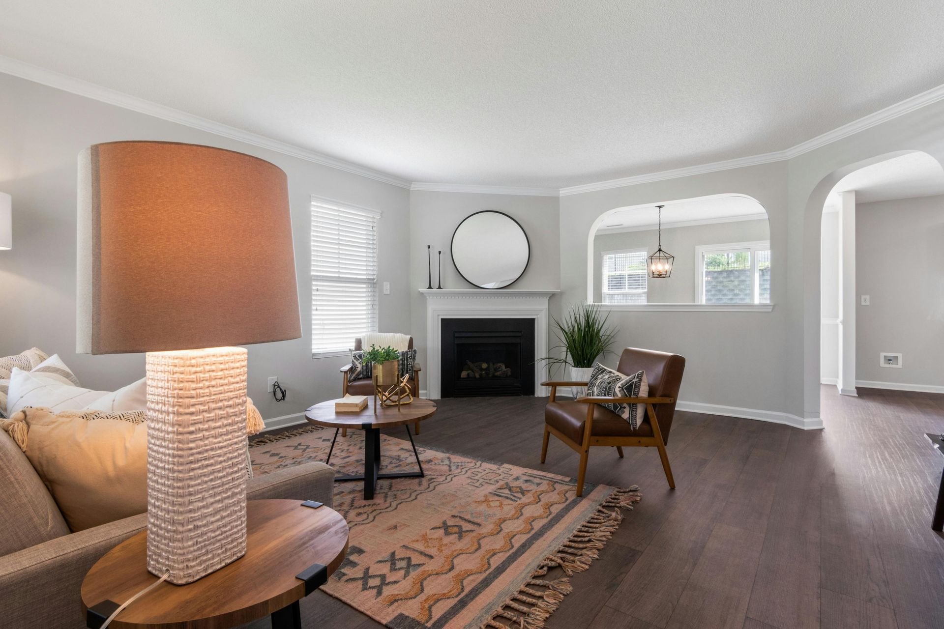 Living room with fireplace, round mirror, brown leather chair, and neutral tones.