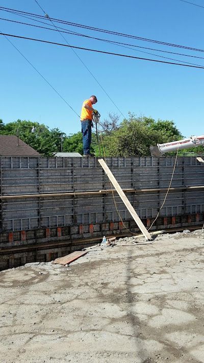 A brick wall surrounds a construction site with a lot of dirt.