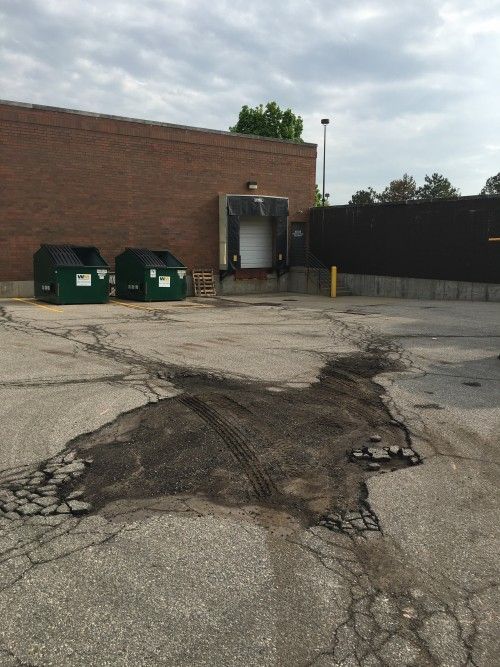 A brick building with green dumpsters in front of it