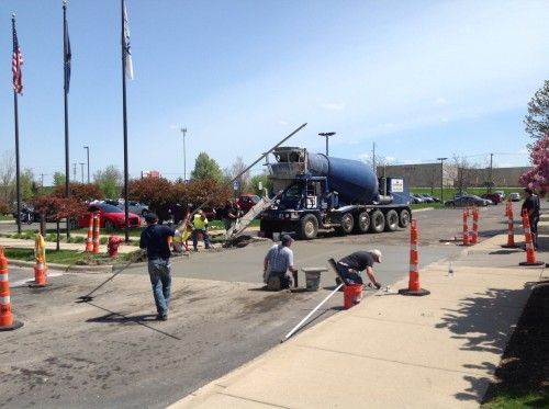 A man is spreading asphalt on the ground with a broom.