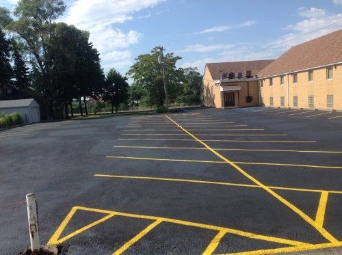 A parking lot with yellow lines and a building in the background