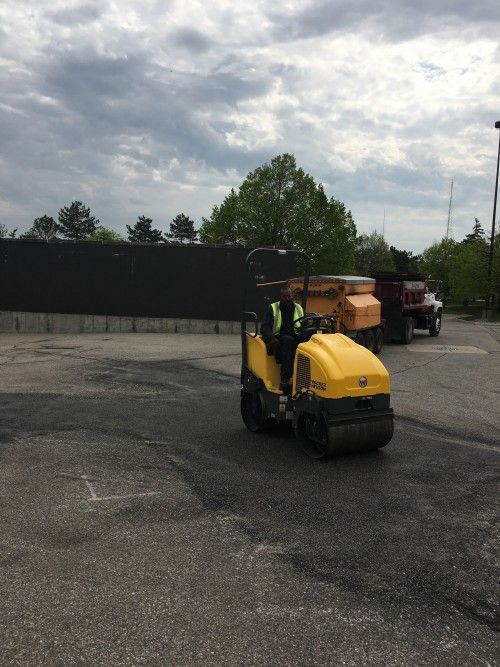 A man is driving a yellow roller in a parking lot