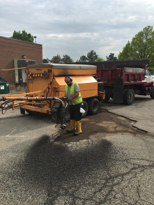 A man in a yellow vest is standing next to a yellow truck.