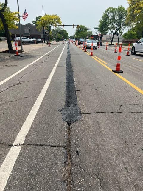 A row of orange and white traffic cones on the side of a road