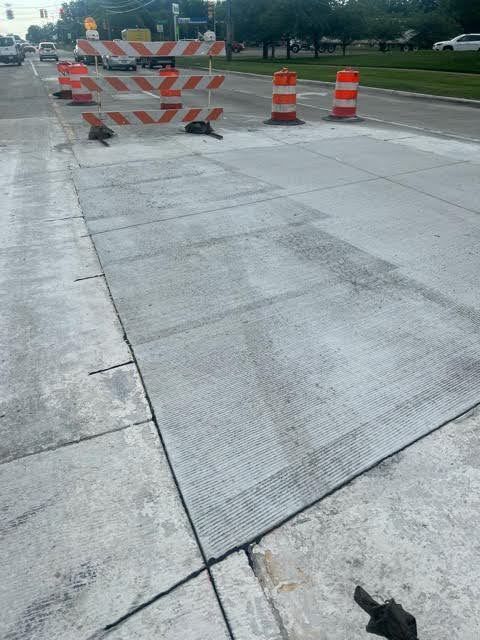 A concrete sidewalk with orange and white barriers on it