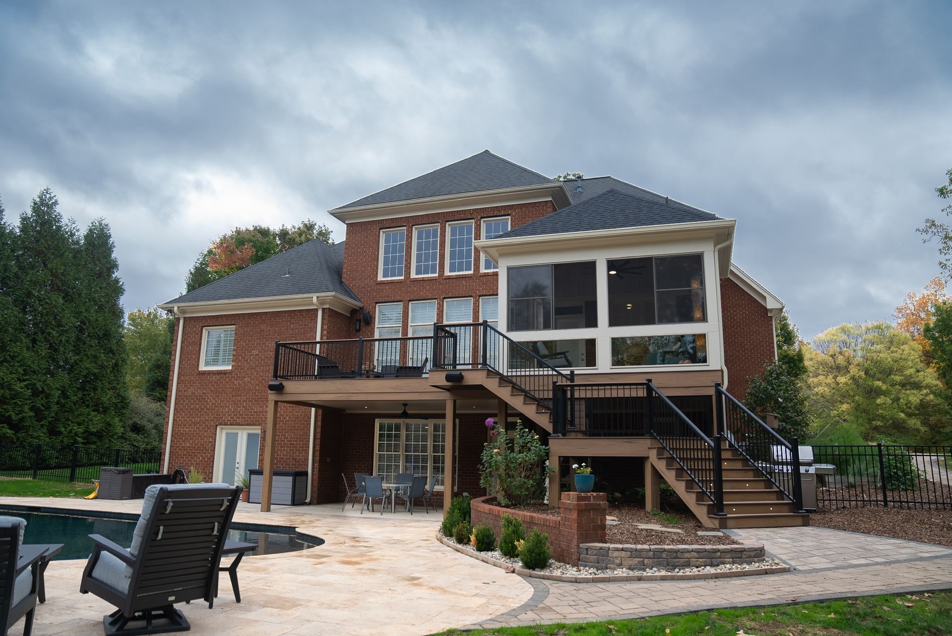 A large brick house with a screened in porch and a swimming pool.