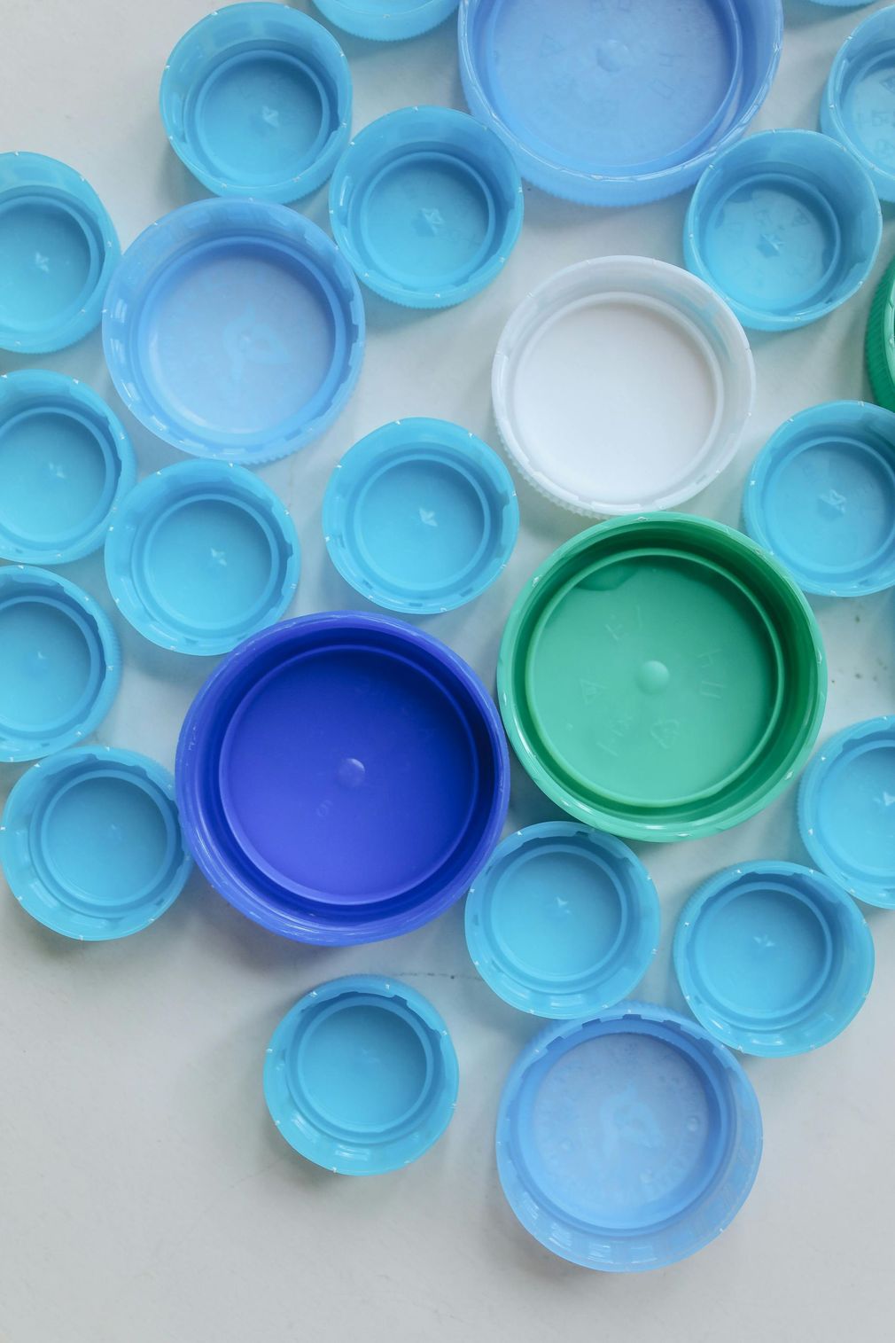 Il y a beaucoup de bouchons de bouteilles en plastique de couleurs différentes sur la table.